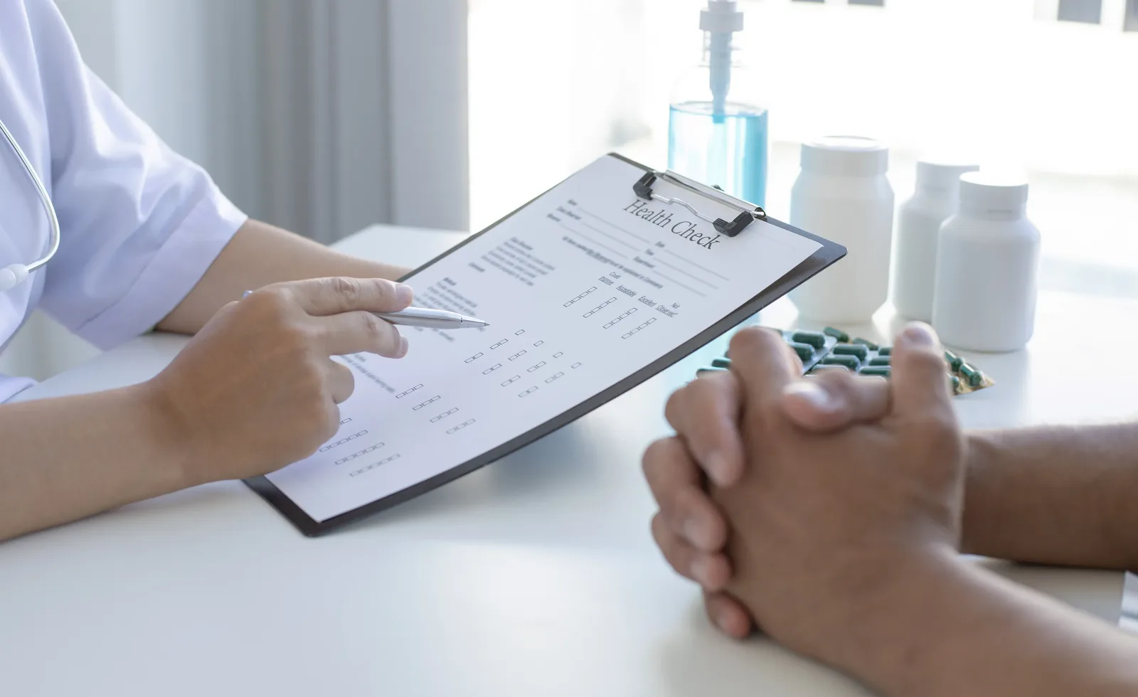 A practitioner reviewing a printed form with a client seated opposite, hands clasped on the table.